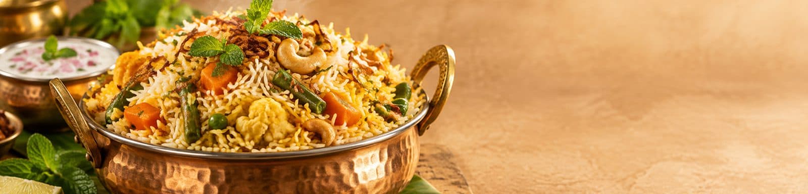 Vegetable biryani in a copper handi with raita